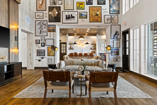 a living room with a couch and chairs and a wall of framed pictures