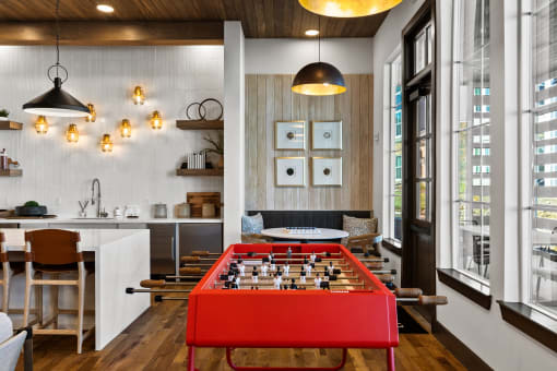 a red foosball table in the middle of a living room with a kitchen