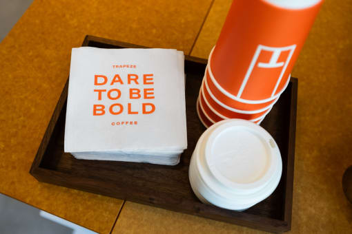 a tray with a cup of coffee and a napkin with dare to be bold