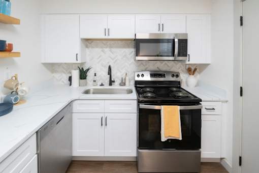 A modern kitchen with white cabinets and a black stove top. at Century Apartments, Memphis, 38117
