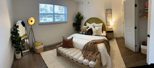 A bedroom with a bed, a window, a nightstand, and a rug.at Century Apartments, Memphis, TN  