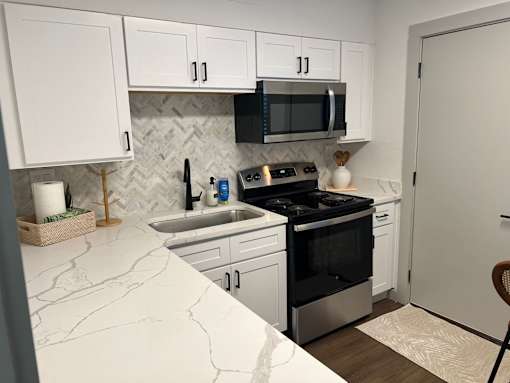 A kitchen with white cabinets and a black stove top oven.at Century Apartments, Memphis  