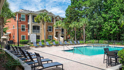 Pool deck with lounge chairs and apartment buildings at Courtney Bend Apartments, South Carolina