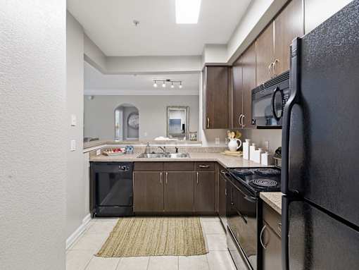 Galley kitchen with stainless steel refrigerator and granite counters at Courtney Bend Apartments, Hardeeville