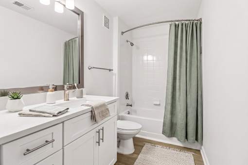 A white bathroom with a green shower curtain.