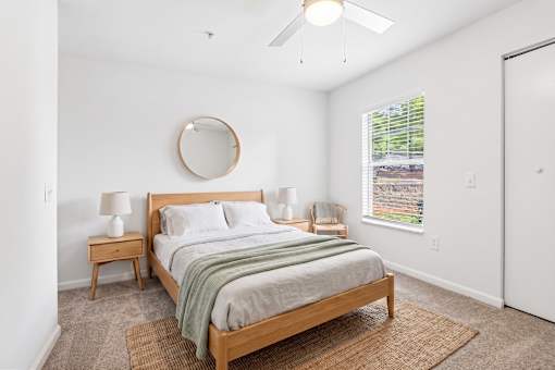 A bedroom with a bed, nightstands, and a window.