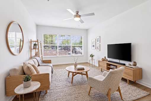 A living room with a couch, a chair, a coffee table, and a television.