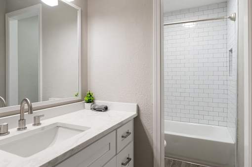 A white bathroom with a sink, mirror at Dunwoody Glen, Atlanta