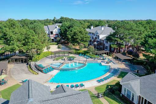 A large swimming pool surrounded by trees and houses at Enclave at Wolfchase Apartments, Memphis, 38016