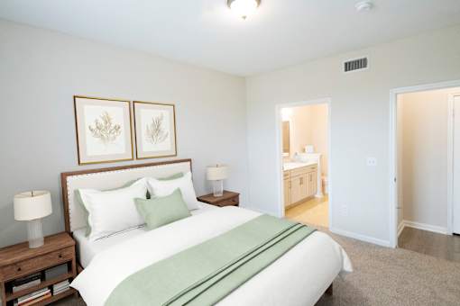 A bedroom with a large bed and two framed pictures above it.