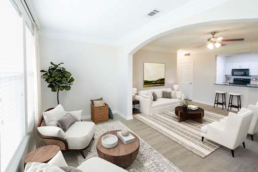 A living room with a white couch, a wooden coffee table, and a potted plant.