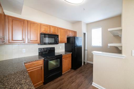 A kitchen with black appliances and wooden cabinets.