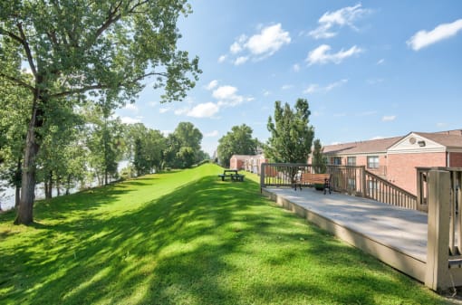 a park with a grassy field next to a building with benches at Brightwaters Apartments, Little Rock, Arkansas