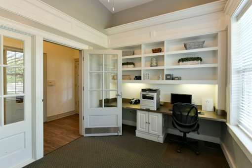A home office with a desk, chair, and shelves.
