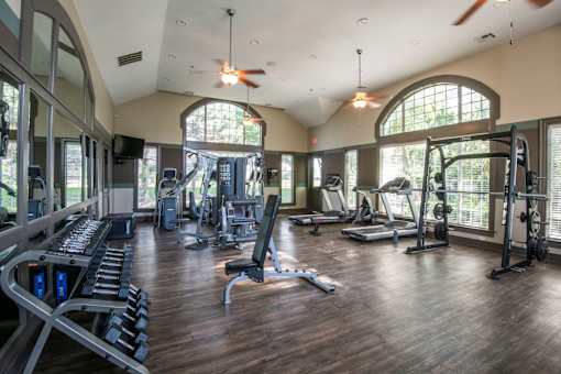 A spacious gym with a variety of equipment and a ceiling fan.