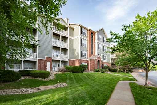 A large apartment complex with a well-maintained lawn and trees.