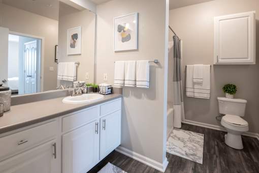 A bathroom with a white toilet, sink, and cabinets.