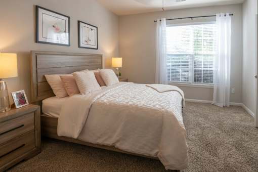 A bedroom with a large bed and two lamps.