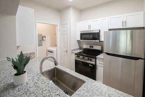 A kitchen with a granite countertop and stainless steel appliances. at Henley at Mirror Lake, Villa Rica, 30180