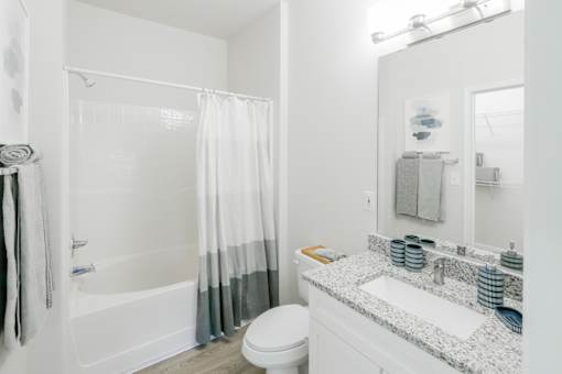 A white bathroom with a toilet, sink, and shower. at Henley at Mirror Lake, Villa Rica, 30180