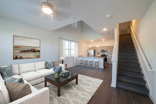 A living room with a white couch and a painting on the wall.