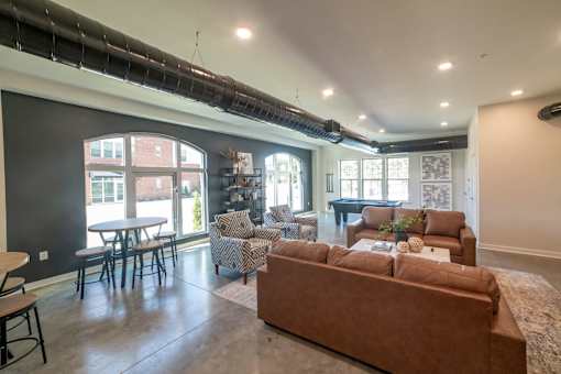 A living room with a brown couch and a dining table.
