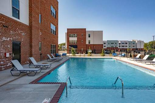 A pool surrounded by chairs and buildings.