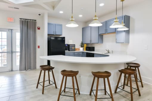 a kitchen with a large island with bar stools and blue cabinets