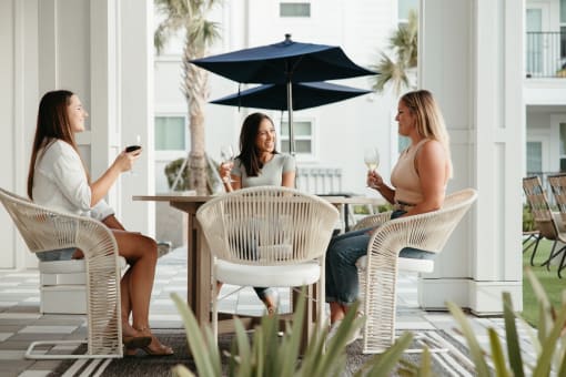 three women sitting at an outdoor table drinking wine at Livano Trinity Apartments, Tennessee, 37207