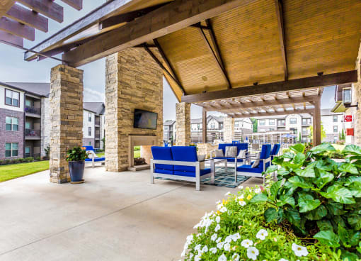 a covered patio with blue chairs and a fireplace
