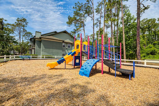 A playground with a yellow slide, a blue slide, and a red and blue climbing frame.