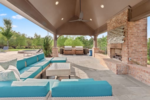 a covered patio with blue couches and a fireplace at The Ridge at Chenal Valley, Little Rock