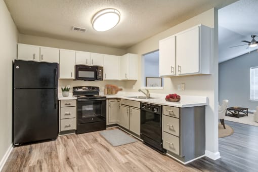 an open kitchen with black appliances and white cabinets  at Serene at Creekstone, Athens, Georgia