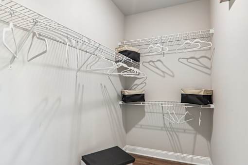 A white closet with clothes hanging on hangers.