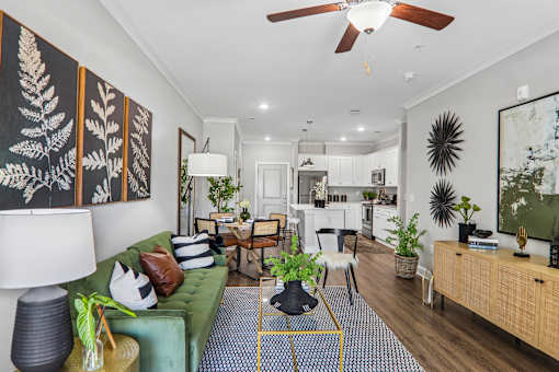 A living room with a green couch and a fan on the ceiling.