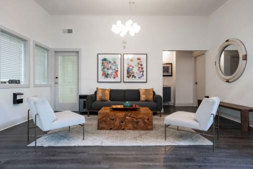 a living room with a black couch and two white chairs at The Summit Apartments, Memphis, 38128