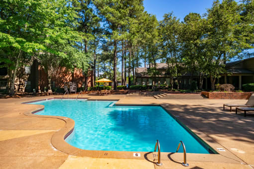 a swimming pool with trees and a building in the background at The Summit Apartments, Memphis, TN, 38128