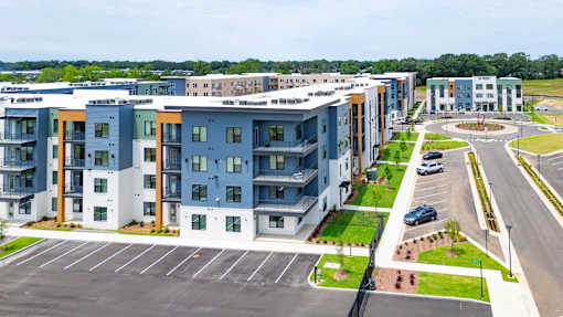 A large apartment complex with a parking lot in front.