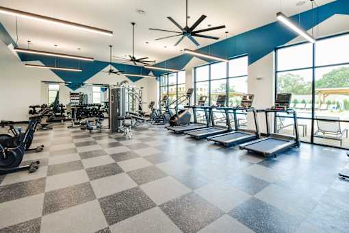 A gym with a variety of equipment including treadmills, weights, and exercise machines.