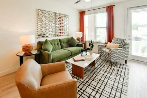 A living room with a green couch, a brown chair, and a black and white plaid area rug