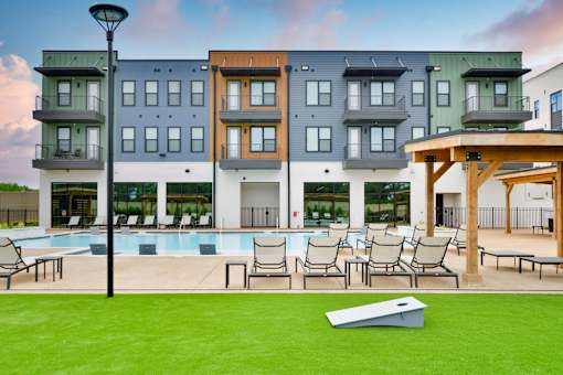 A modern apartment complex with a pool and lounge area.