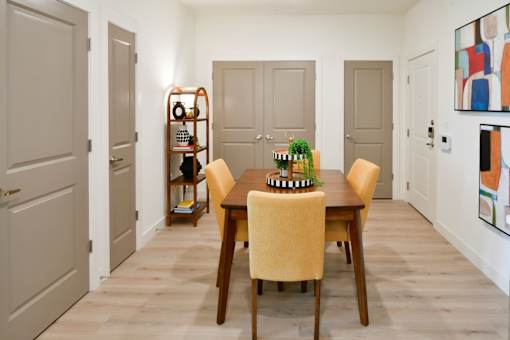 A dining room with a table set for four and a bookshelf.
