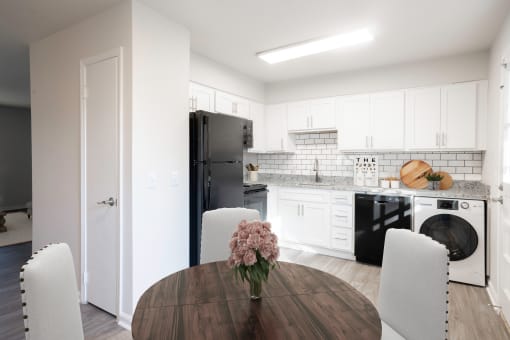 a kitchen and dining room with white cabinets and black appliances at Carrolton in Carrolton, GA 30117