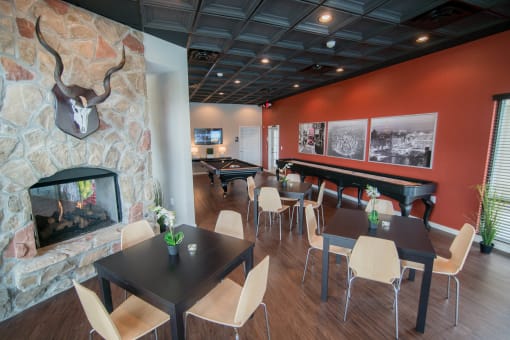 a dining room with tables and chairs and a fireplace at The Villa at River Pointe, Maumelle, AR 72213