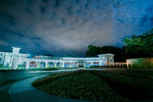 the facade of a building at night with lights on it at The Villa at River Pointe, Maumelle, Arkansas