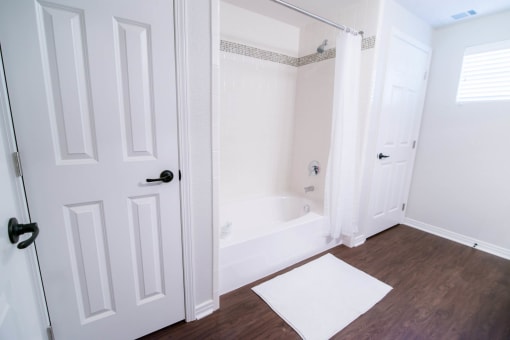 a white bathroom with a tub and a white door at The Villa at River Pointe, Arkansas, 72213