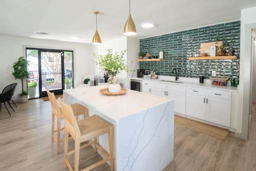 Kitchen with a white marble island and wooden chairs at The Garden District Apartments, Tennessee