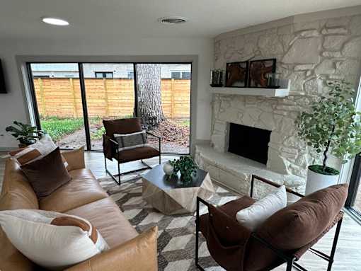 A living room with a fireplace and a stone wall.at The Garden District Apartments, Germantown, TN  
