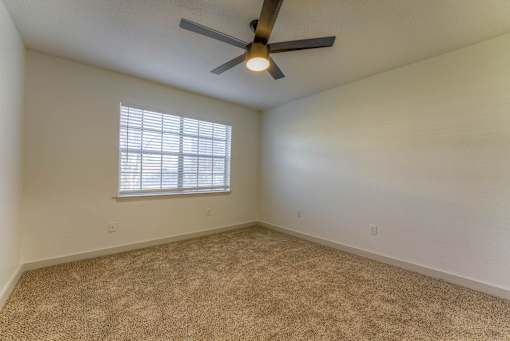 A room with a ceiling fan and a window with blinds.at The Garden District Apartments, Germantown  