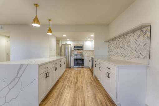 A kitchen with white cabinets and a wooden floor.at The Garden District Apartments, Tennessee, 38138